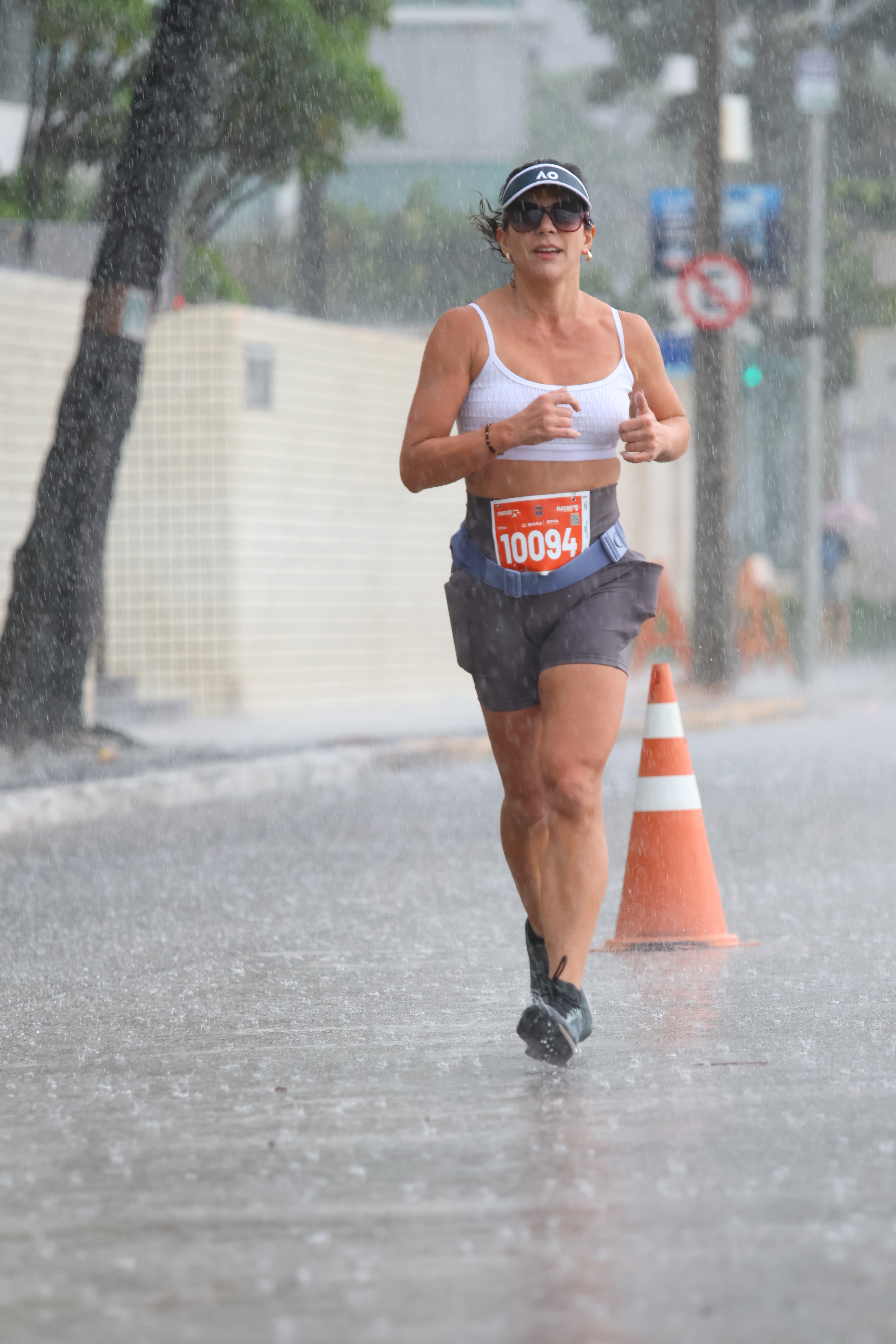 Mari Walks running in heavy rain during a road race, wearing race bib number 10094
